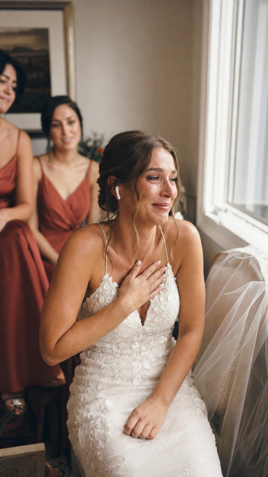 A bride on her wedding morning, hand over her chest, listening to a song from her groom